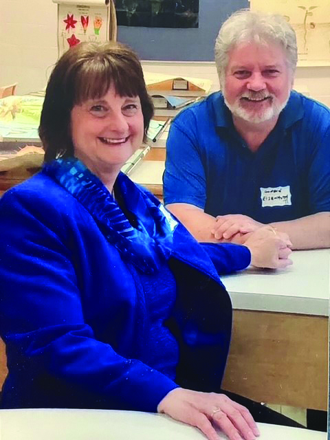 Sheri and Gordon sitting in the same school desks where their story began.